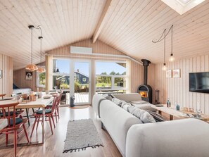Interior acogedor de una cabaña con comedor, sofá y chimenea de leña.