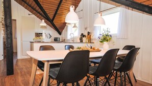 Un espace de salle à manger moderne avec une table en bois, des chaises noires et des luminaires suspendus.