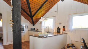 Une cuisine moderne dotée d’un îlot central, de planchers en bois et d’un plafond en pente.