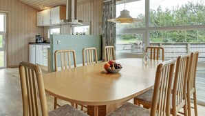 Een moderne keuken met houten keukenkastjes, een roestvrijstalen afzuigkap en een eethoek met een houten tafel en stoelen.