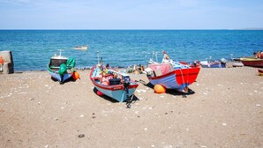 Een strand met verschillende boten afgemeerd, een helderblauwe lucht en een rustige zee.