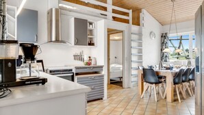 A modern kitchen with a coffee machine, a dining area with chairs, and a view of the outdoors. - "Palli" - 600m from the sea by Interhome (Thisted)