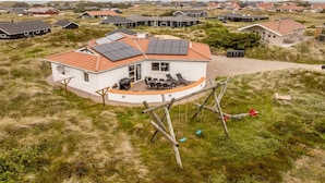 A house with a curved roof, solar panels, and a patio with outdoor furniture. - "Palli" - 600m from the sea by Interhome (Thisted)