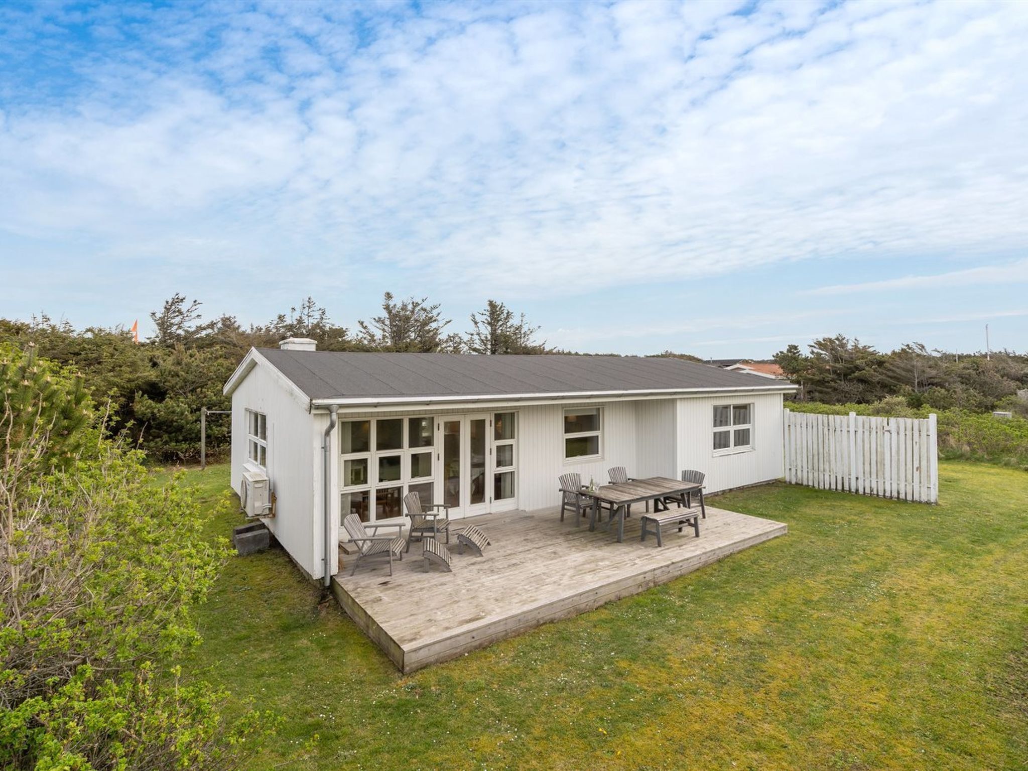 A single-story house with a covered patio, a fenced yard, and a view of the surrounding landscape.