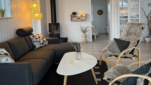 En moderne stue med sofa, lænestole, sofabord og pejs.