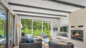 Una sala de estar moderna con un sofá, sillas, un televisor y una chimenea.
