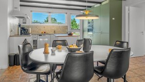 Una cocina moderna con comedor, ventanas amplias y vistas a zonas verdes.