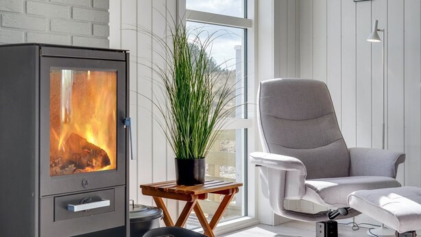 A modern living room with a wood-burning stove, a comfortable chair, and a potted plant. - "Ibo" - 900m from the sea by Interhome (Thisted)