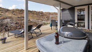 A covered outdoor area with a barbecue grill, lounge chairs, and a bottle of beer. - "Ibo" - 900m from the sea by Interhome (Thisted)