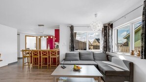 En moderne stue med en modulsofa, et spiseområde med et træbord og stole, og et køkken i baggrunden.