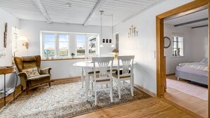 Ein gemütliches Zimmer mit Essbereich, Holzboden und einem Bett im angrenzenden Raum.