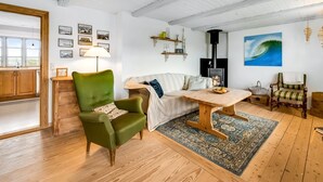 Ein gemütliches Wohnzimmer mit einem grünen Sessel, einer Couch, einem Holztisch und einem Kamin.