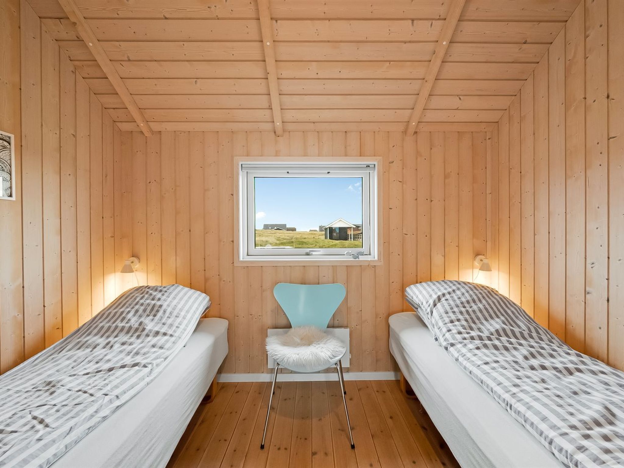 Une cabine avec deux lits, une fenêtre donnant sur un beau paysage et une petite chaise.