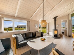 Een moderne woonkamer met een leren bank, een witte tafel en een houtkachel.
