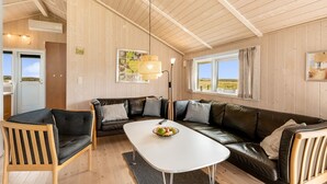 Une pièce chaleureuse avec un plafond en bois, un canapé en cuir noir, une table blanche et une chaise en bois.