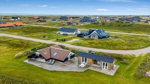 An aerial view of a residential area with houses, a large open grassy field, and a paved road. - "Olesia" - 250m from the sea by Interhome (Harboøre)