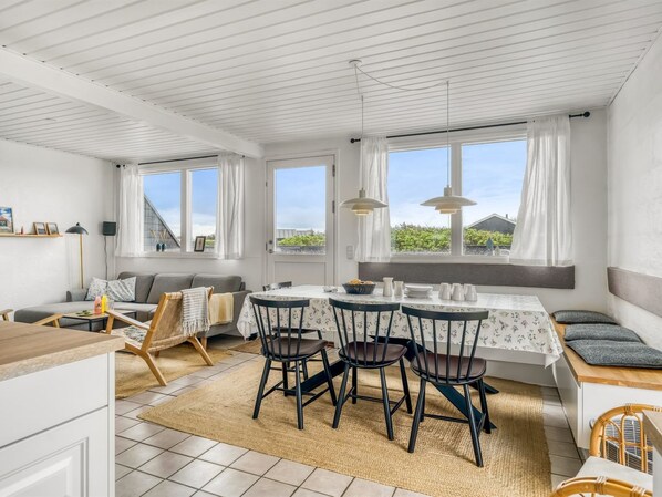 A modern kitchen with a dining area, large windows, and a view of the outdoors.