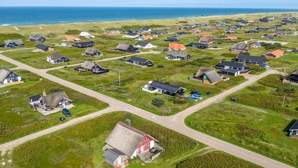 Vue aérienne d’un village côtier avec ses maisons, ses routes et sa plage.