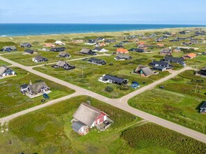 Luchtbeeld van een kustdorp met huizen, wegen en een strand.