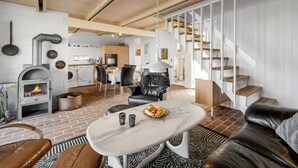 Un salon moderne avec une cheminée, des meubles en cuir et un escalier.