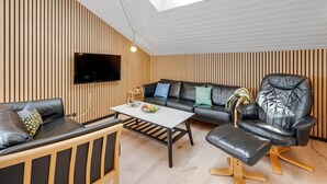A modern living room with a sofa, a coffee table, a TV, and a chair. - "Arla" - 200m from the sea by Interhome (Harboøre)