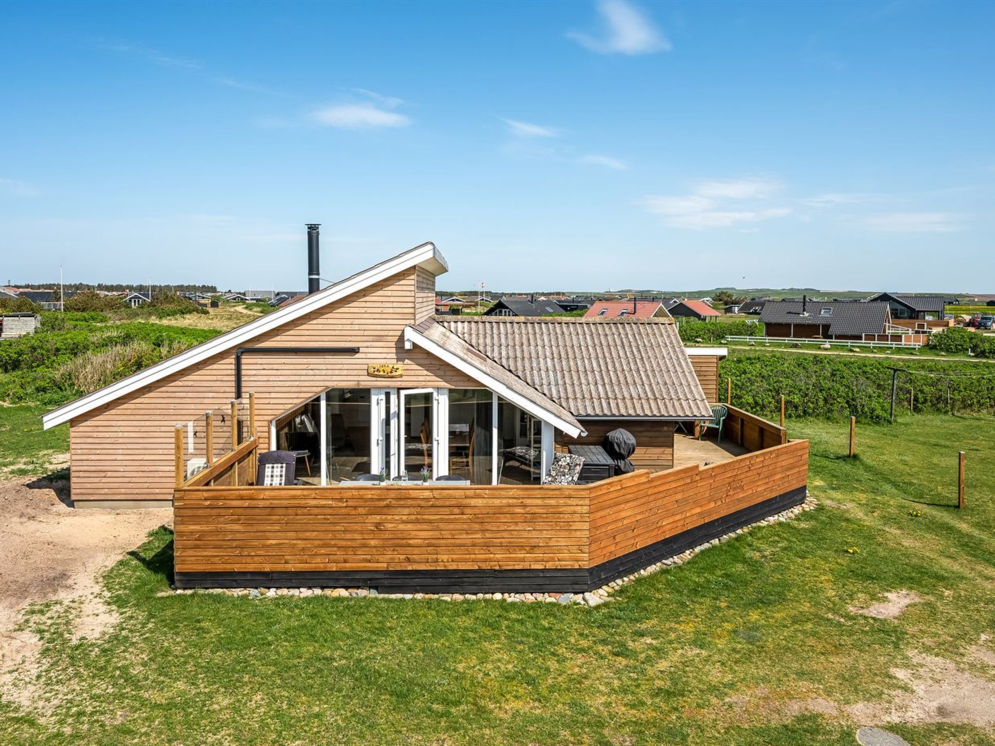 A modern wooden cabin with a sloped roof, a covered patio, and a chimney.