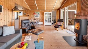 A cozy cabin interior with a wooden interior, a fireplace, a sofa, a dining area, and a kitchen. - "Brigit" - 200m from the sea by Interhome (Harboøre)