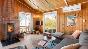 A cozy cabin interior with a fireplace, wooden walls, a sofa, and a television. - "Brigit" - 200m from the sea by Interhome (Harboøre)