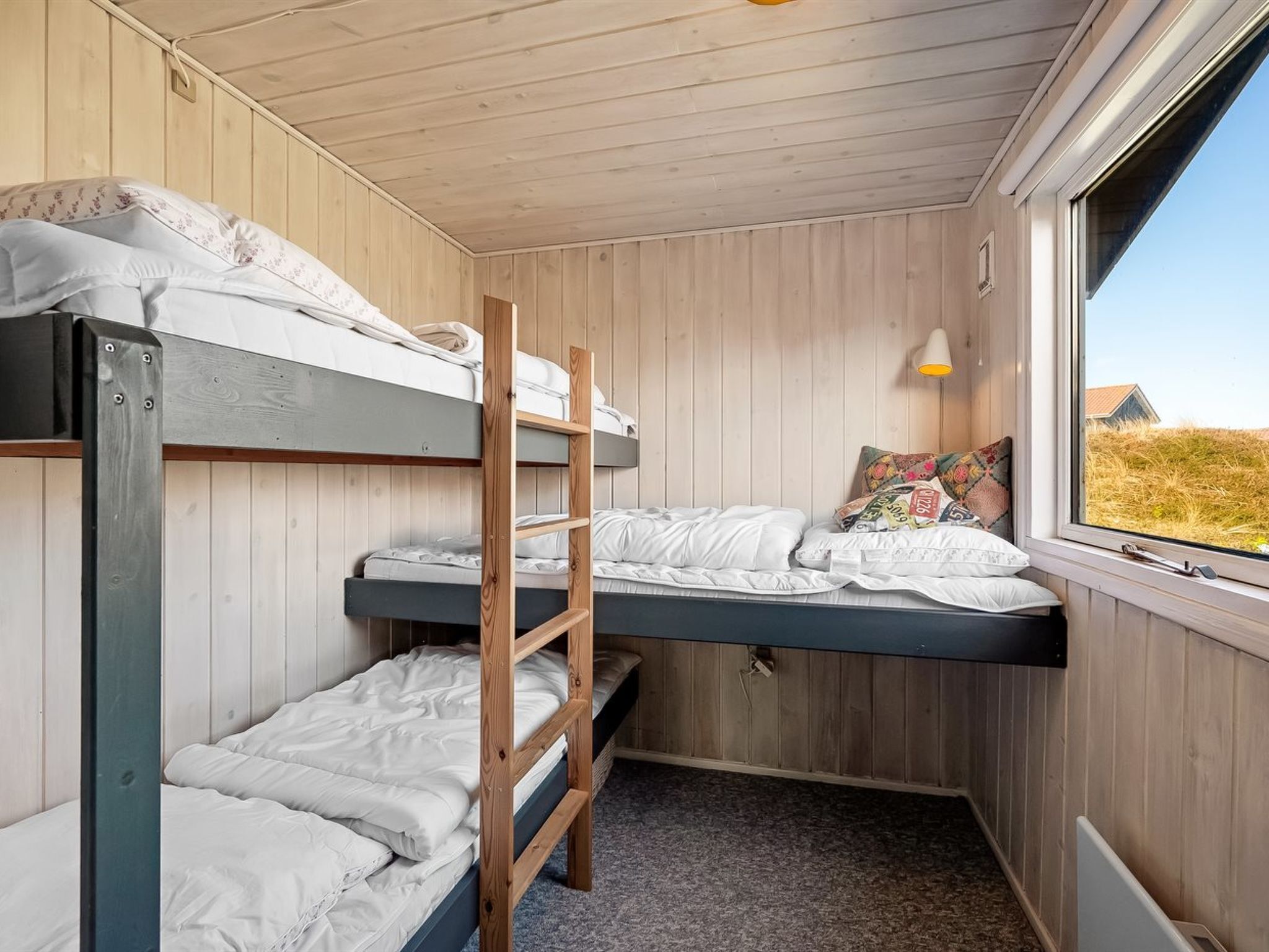 A bunk bed room with wooden walls and a window.