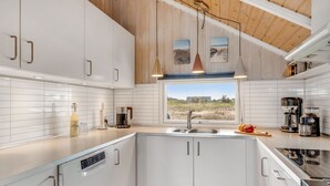 Een moderne keuken met witte kastjes, een groot raam en een houten plafond.