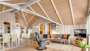 Ruime loft met hoge plafonds, een eethoek, een zithoek met bank en televisie, en een keuken.