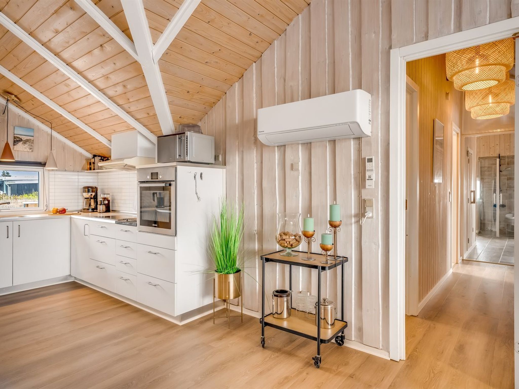 A modern kitchen with white cabinets, a wooden ceiling, and a small dining area with a table and chairs.