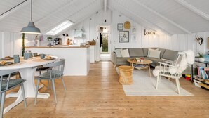 Un loft espacioso con techo alto, una zona de cocina, una mesa de comedor con sillas, un sofá y una estantería.