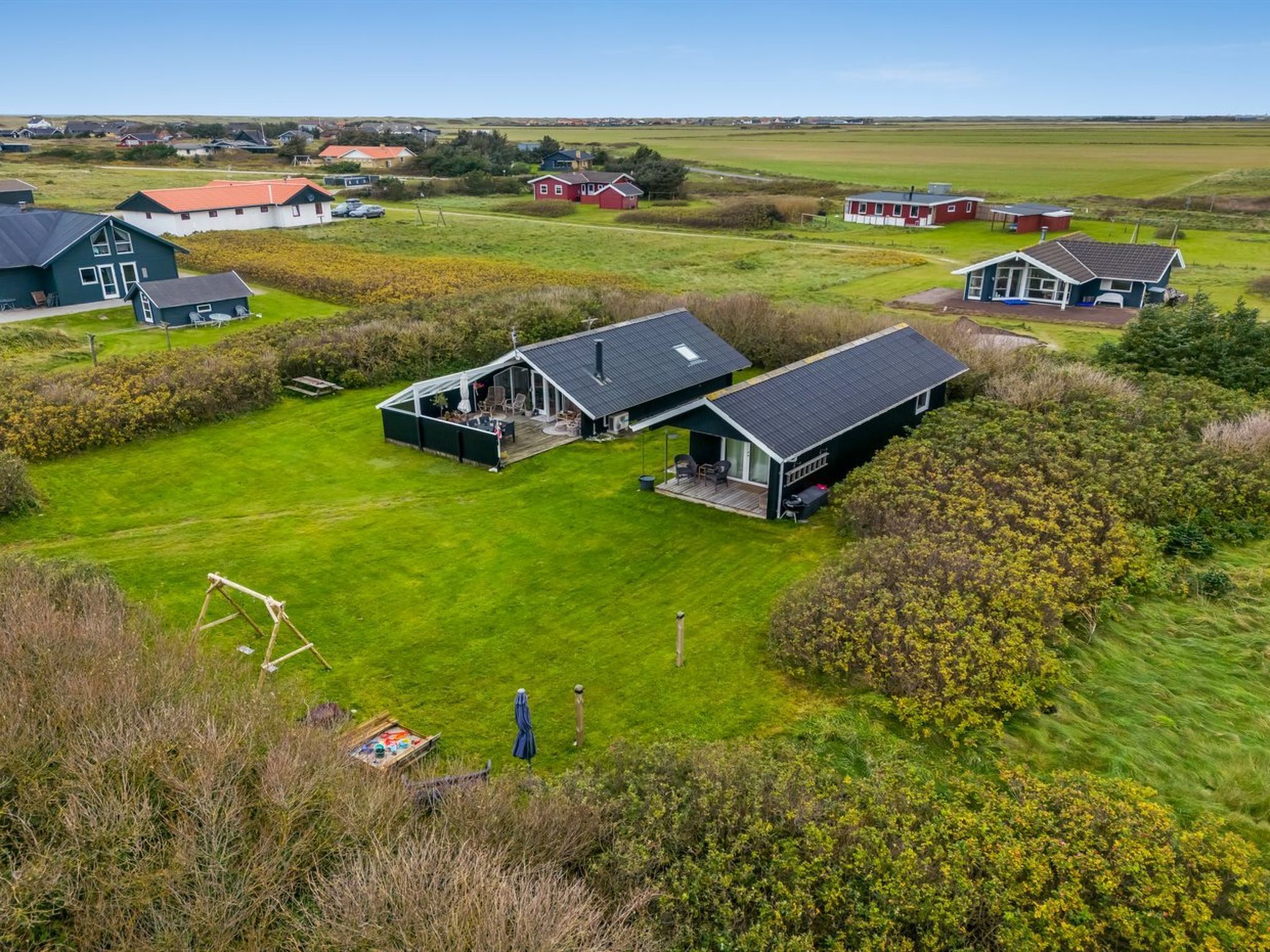 A large, modern house with a spacious deck and a large lawn.