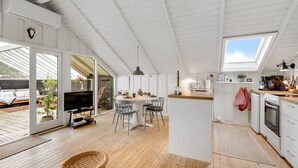 Una cocina moderna con tragaluz, suelo de madera y un comedor con televisor.