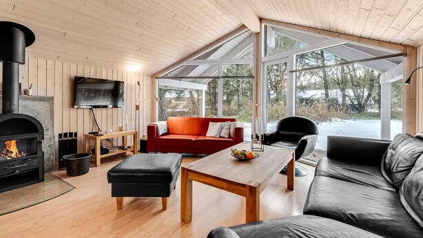 Una sala de estar moderna con chimenea, un sofá rojo, un sofá de cuero negro y una mesa de centro de madera.