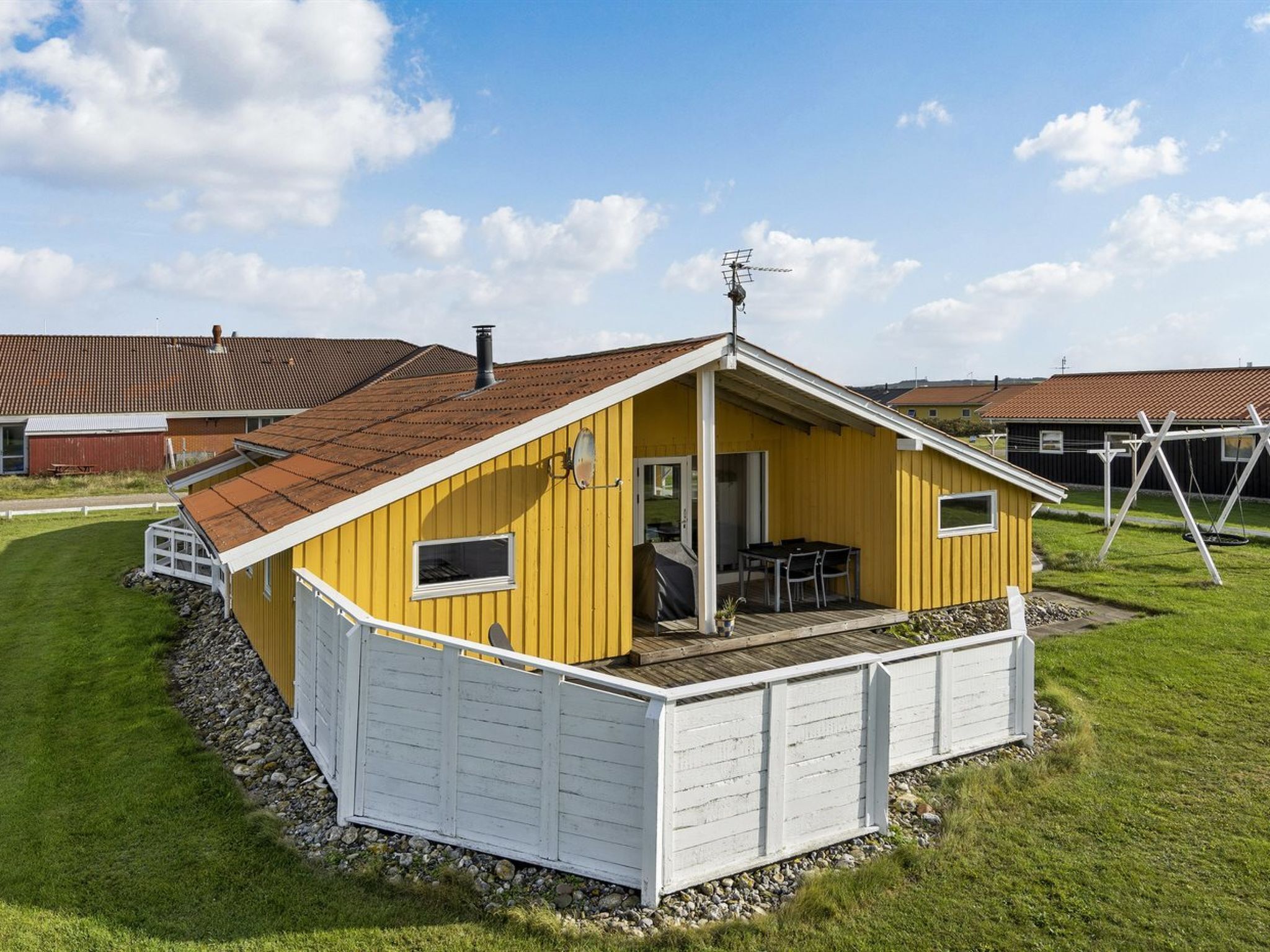 A yellow single-story house with a white garage, a covered patio, and a small deck.
