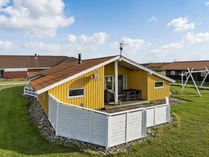 Et gult etplanshus med en hvid garage, en overdækket terrasse og en lille altan.