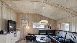 A modern living room with a wooden ceiling, a black leather sofa, a round coffee table, and a flat-screen TV. - "Hebba" - 300m from the sea by Interhome (Harboøre)
