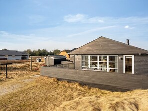 Une maison moderne dotée d’un grand porche vitré, d’un garage et d’une plaque portant le numéro « 2 ».
