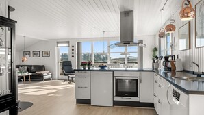 A modern kitchen with a central island, built-in oven, and pendant lighting.