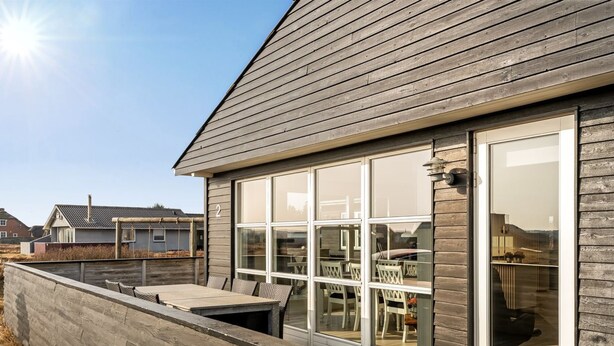 A residential building with a wooden exterior, large windows, and a deck area.