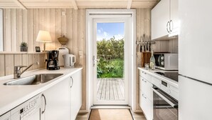 A compact kitchen with white cabinets, a sink, a coffee maker, and a microwave. - "Tanna" - 330m to the fjord by Interhome (Lemvig)