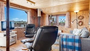 A cozy cabin interior with a wooden ceiling, a fireplace, a TV, and a view of the outdoors. - "Beatrice" - 150m from the sea by Interhome (Lemvig)