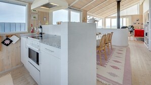 Et moderne køkken med en stor ø, træloft og store vinduer.