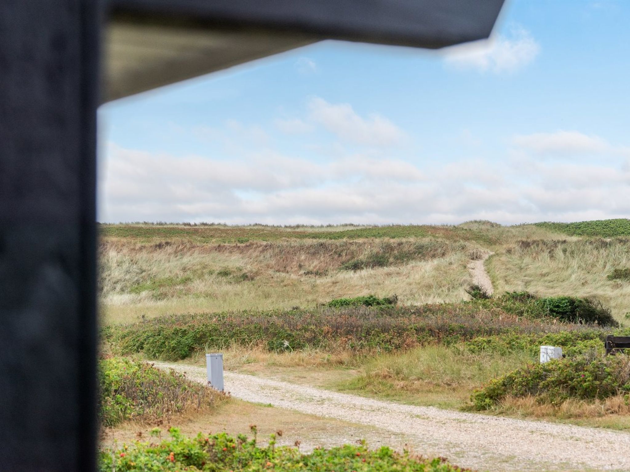A gravel path leading through a natural landscape with grassy hills and sparse vegetation.