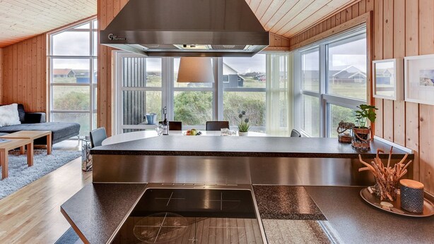 Una cocina moderna con una isla central, ventanas amplias y vigas de madera en el techo.