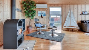 Una sala de estar acogedora con paneles de madera, una chimenea, una planta en maceta, un modelo de velero y una silla moderna.