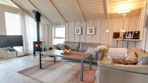 A cozy living room with a fireplace, leather sofas, a coffee table, and a TV.
