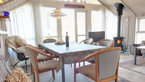 A cozy room with a dining table, chairs, a sofa, a fireplace, and a TV.